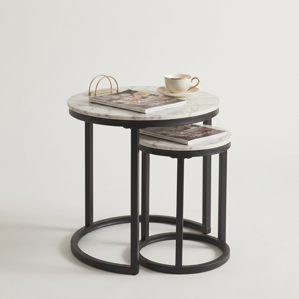 Homebox Roma set of two round nesting tables with glossy sintered-stone tabletops and metal bases in different sizes, designed for a contemporary studio-apartment living room.